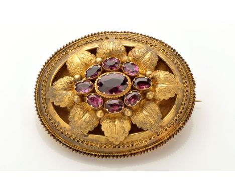 A Victorian yellow metal and amethyst brooch, the oval facet cut central amethyst surrounded by eight smaller amethysts on a 