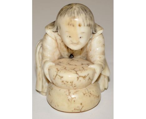 Japanese bone Netsuke, as a young boy grinding corn with quern  stones, height 3.7cms.
