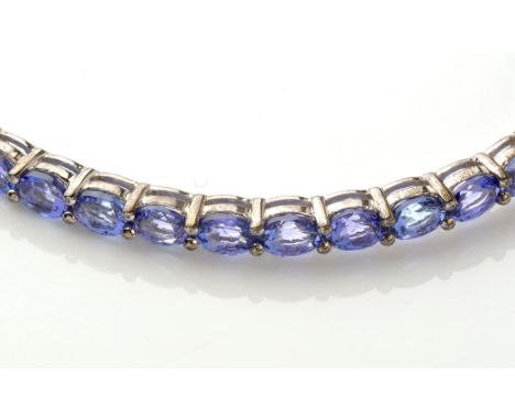 A tanzanite bangle, with fifteen oval facet cut tanzanites set to a silver bangle, 7cms diameter.