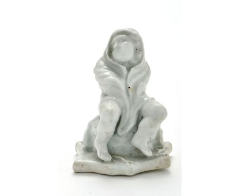 English 'Dry Edge' porcelain figure of Winter, modelled as a seated putto figure wrapped with a cloth around his head, arms a
