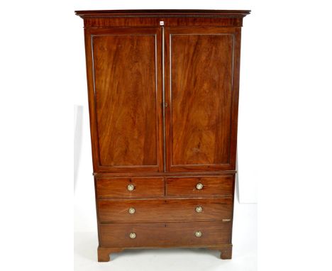 A George III gentleman's mahogany wardrobe, with a flared cornice above a pair of panel doors and dummy drawers enclosing han