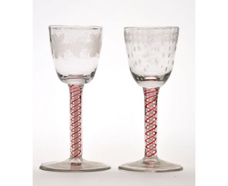 Two engraved opaque and red enamel twist wine glasses, the round funnel bowls above double series stems and slight conical fe