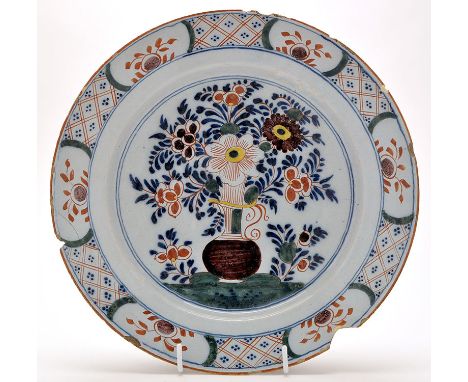 Delftware polychrome dish, with vase of flowers enclosed by panel and lattice border, 18th Century, diameter 35.5cms.