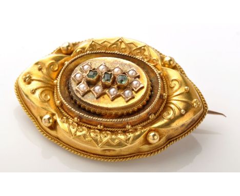 A Victorian Etruscan style yellow metal, emerald and seed pearl brooch, the three central emeralds step cut, surrounded by a 