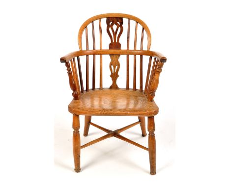 An early 19th Century small size solid elm seat Windsor chair, comb spindle and pierced splat back, raised on turned tapering