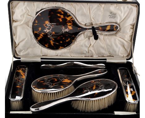 A George V silver and tortoiseshell dressing table set, by William Adams Ltd., Birmingham 1925, with foliated scroll decorati