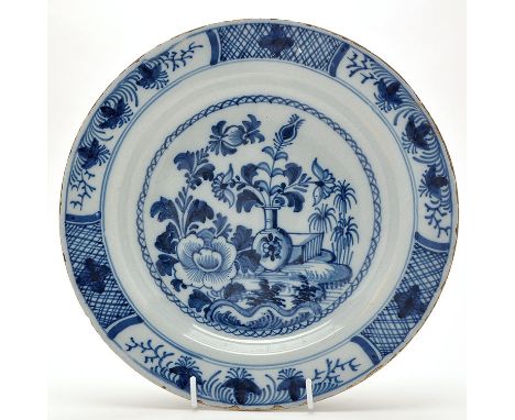 Delftware blue and white dish, painted with vase of flowers in garden setting enclosed by triple panel and lattice border, 18