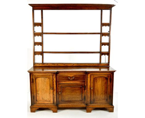 A George III oak  breakfront dresser with open delft rack above, fitted a short drawer and cupboard to the centre, flanked by