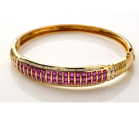 A ruby, diamond and yellow metal bangle, set with eighteen rows of three square facet cut rubies, bordered by channel set bri