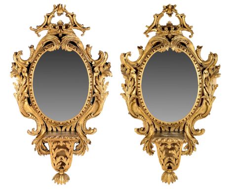 A pair of 19th Century gilt wood and gesso oval-shaped wall mirrors, in rococo design frames, each with gadrooned square-shap