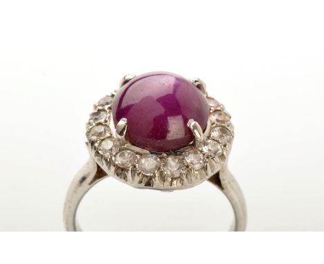 A star ruby and white stone cluster ring, the star ruby cabouchon measuring 9.5mm x 6.6mm, four claw set surrounded by white 