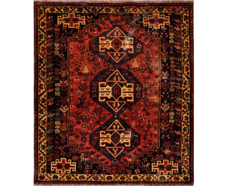 Shiraz rug, red stepped lozenge field with three step medallions enclosed by blue and ivory borders, 170 x 130cms.