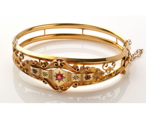 A Victorian yellow metal, ruby and diamond bangle, the three graduated circular facet cut rubies separated by two diamonds, a