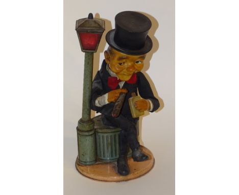 A vintage battery operated tin plate toy, modelled as a drunk holding a bottle and cigar, sitting on a dustbin beside lamp po