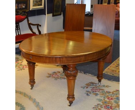 A Victorian mahogany extending D-end dining table, with two additional leaves, raised on carved turned supports with ceramic 