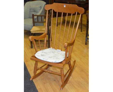 A modern light oak rocking chair, with spindle back and tie cushion seat, 103cm high