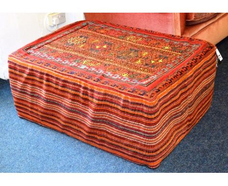 An antique Kelim pouffe, decorated with multicoloured orange, green and blue geometric designs over red ground, 44cm high x 1