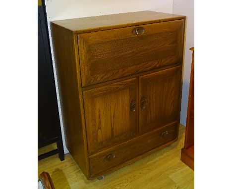 An Ercol Windsor style elm secretaire cupboard, with fall front enclosing fitted compartment above two doors and drawer, labe