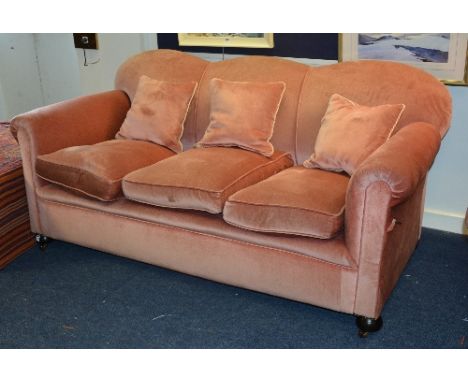 A vintage three seater drop end sofa, upholstered in later pink velour, raised on bun feet, 82cm high x 182cm wide