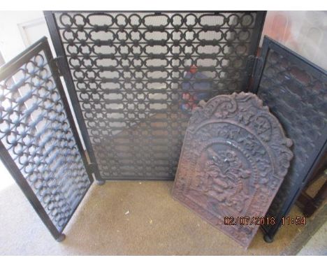 A Victorian cast iron fire-back, together with a black painted fretwork fireguard 