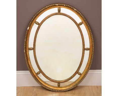 A Regency style gilt oval wall mirror with a mirrored slip frame85 x 64cmSome of the gesso work is missing.