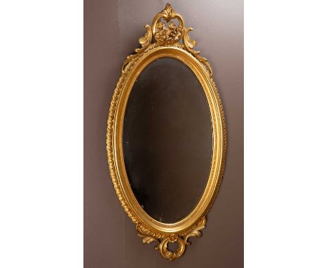 An antique gilt oval wall mirror with scrolling crest and moulded frame67cm wide x 131cm highQty: 1The mirror plate with some