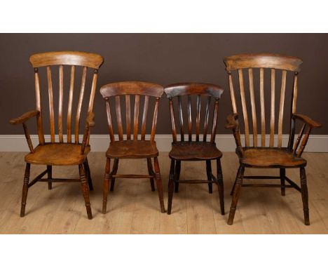 A set of four comb back dining chairs to include two carvers, the comb backs above elm seats on turned legs united by an H fr