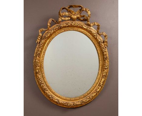 A gilt framed circular wall mirror surmounted by a bowed ribbon with oak and laurel decoration to the frame81cm high x 62cm w