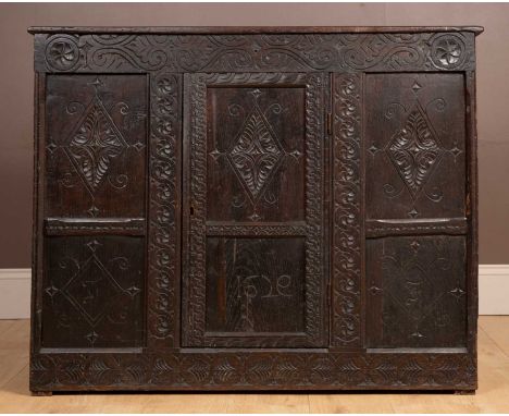 An oak cupboard stamped 1629, with carved panelled front and sides, and a later small gallery to the top, lozenge marquetry e