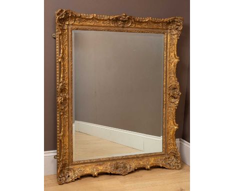 A large rectangular wall mirror in a gilt frame with sea scrolls and foliate decoration and a bevelled plate94cm x 115cmIn ge