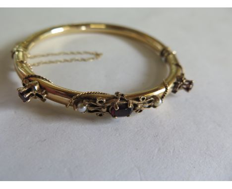 A 14ct yellow gold bangle set with pearls and garnets 6cm wide - approx 11.8 grams, minor denting, otherwise generally good 