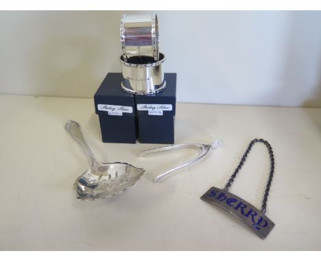 A mixed silver lot, pairs of boxed napkn rings, blue enamelled sherry label, pair of wishbone sugar tongs and sifting spoon, 