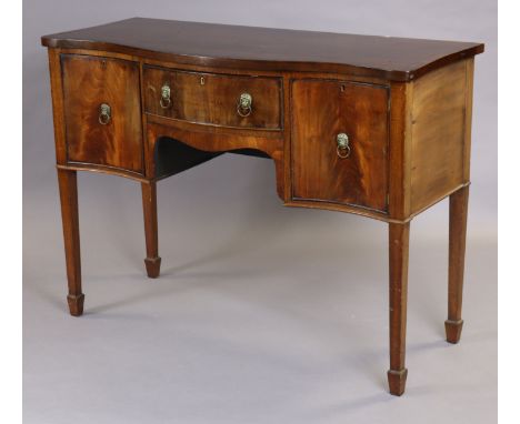 A Georgian mahogany sideboard of serpentine shape, with crossbanded top, central frieze drawer and cupboard either side, all 
