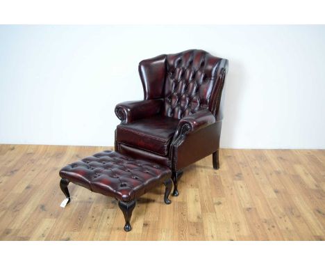 A reproduction 'Chesterfield' wingback armchair, the button backrest over scrolled elbow rests raised on squat cabriole feet,