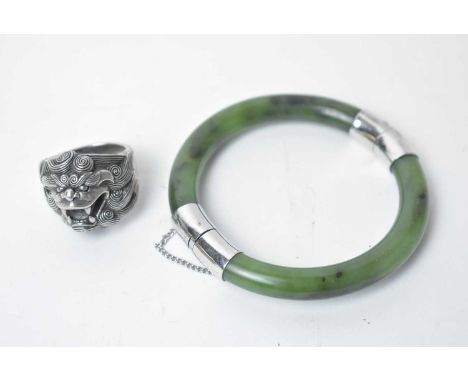 A Chinese silver dog of foo pattern ring, with character mark to inside shank, 35.8g; together with a green stone bangle. (2)