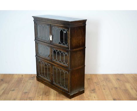 Simpoles Chapter: A 1920s oak three sectional bookcase, the rectangular moulded top over two door hinged lead glazed cabinets