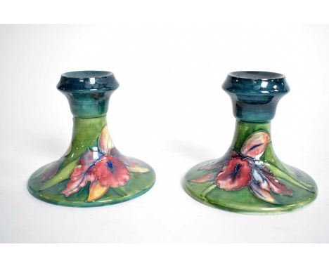 A pair of Moorcroft ceramic candlesticks, each tube line decorated with flowers, with impressed marks and paper label to unde