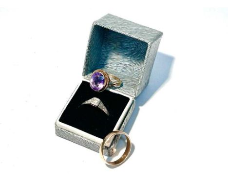 An amethyst ring on 9ct gold shank; a white stone ring on gold shank; and a 9ct yellow gold wedding band, 8.3g gross. 