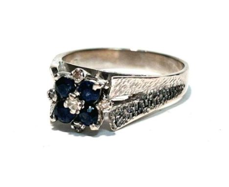 A sapphire and diamond ring, the four circular facet set sapphires surrounded by 8-cut diamonds flanked by textured 18ct whit