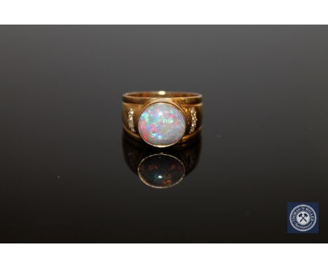 An 18ct gold opal and diamond ring, the oval cabochon white opal in a rubbed over setting, the shoulders set with eight brill