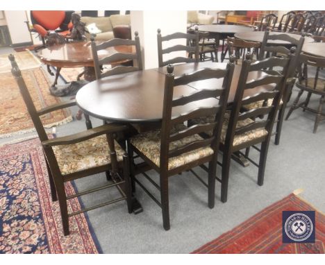 An oval oak extending dining table with leaf, together with a set of six ladder backed dining chairs