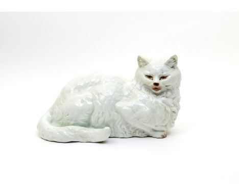 A lifesize Continental porcelain model of a cat  late 19th century, after Meissen, recumbent with head turned to dexter and i