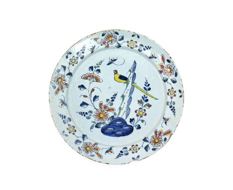 A large delftware charger  c.1740, probably Bristol, painted in the Chinese manner with a long-tailed yellow bird perched on 