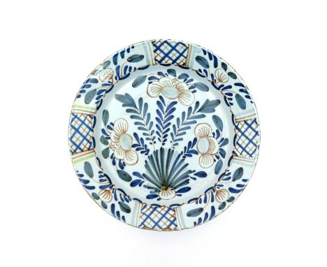 A large delftware charger  c.1740, simply decorated in blue, green, red and yellow enamels with naive flowers issuing from fe