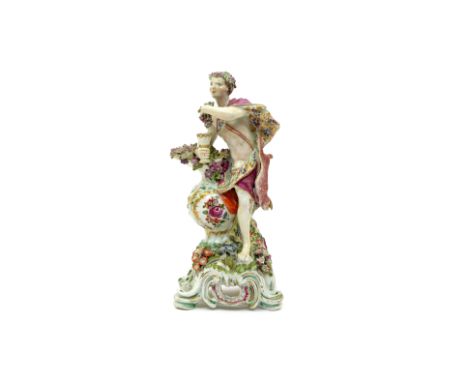 A large Bow figure of Autumn  c.1760-65, modelled as a young Bacchus leaning on a tall ewer brimming with grapes and painted 