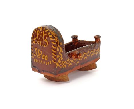 A slipware model of a cradle  dated 1800, incised and decorated in cream slip with continuous scrolls and dashes, the cradle'