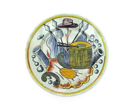 A large Delft charger late 18th century, brightly painted with war motifs including cannon, flags, a large drum and a hat on 