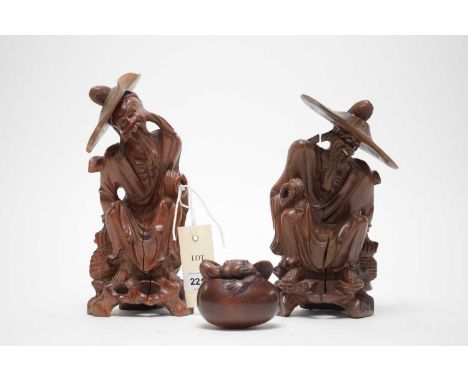 A pair of Japanese carved root wood figures of men, each modelled wearing a hat; together with a Japanese carved wood netsuke