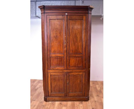 A large 19th Century mahogany floor standing corner cabinet, with upper and lower double door cabinets opening to reveal a sh