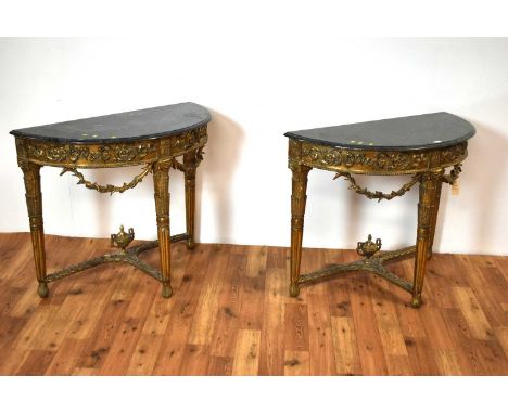 A pair of ornate Georgian style marble-topped and gold painted demi lune console tables, with floral scrollwork decoration an